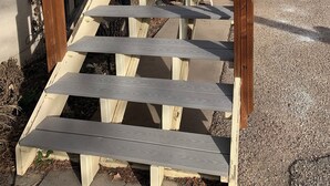 A wooden staircase with a black railing leading to a building with a beige exterior. - Bard's Inn (Cedar City)