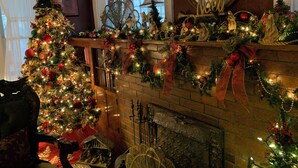 A warmly decorated living room with a fireplace, a Christmas tree, and festive ornaments. - Bard's Inn (Cedar City)