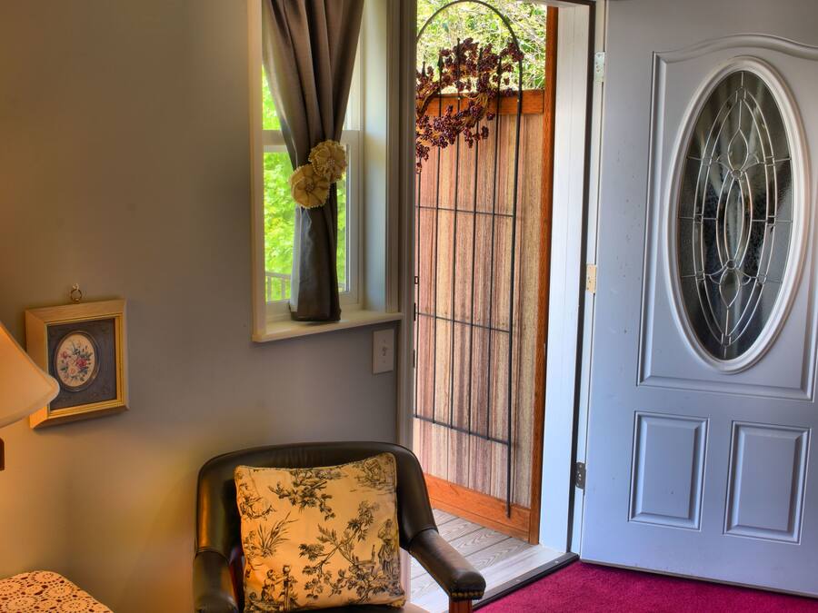 A room with a lamp, a chair with a floral cushion, a framed picture, and a door with a glass panel.