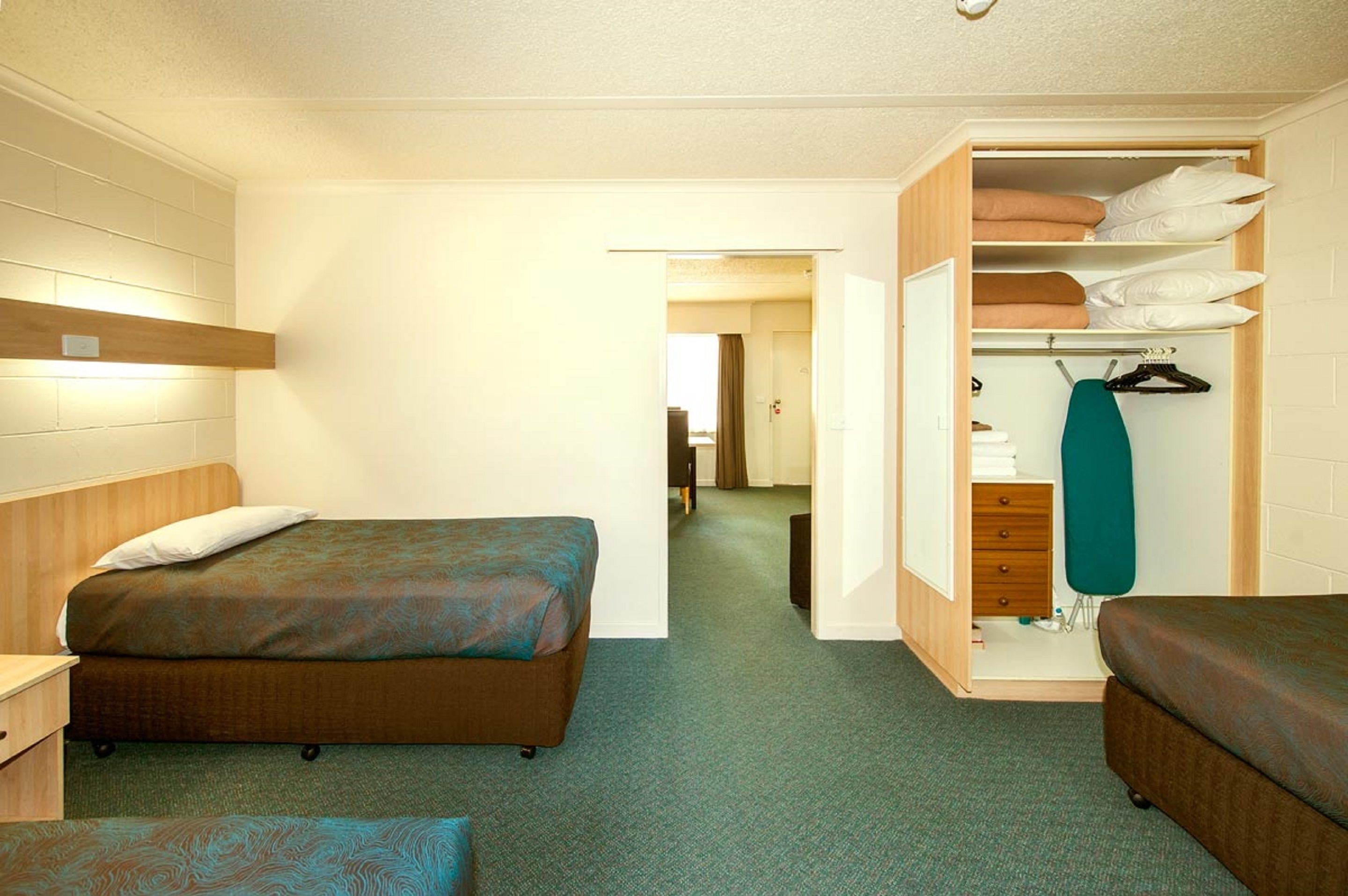 Een hotelkamer met een bed, een klein bureau, een kledingkast en een inloopkast.