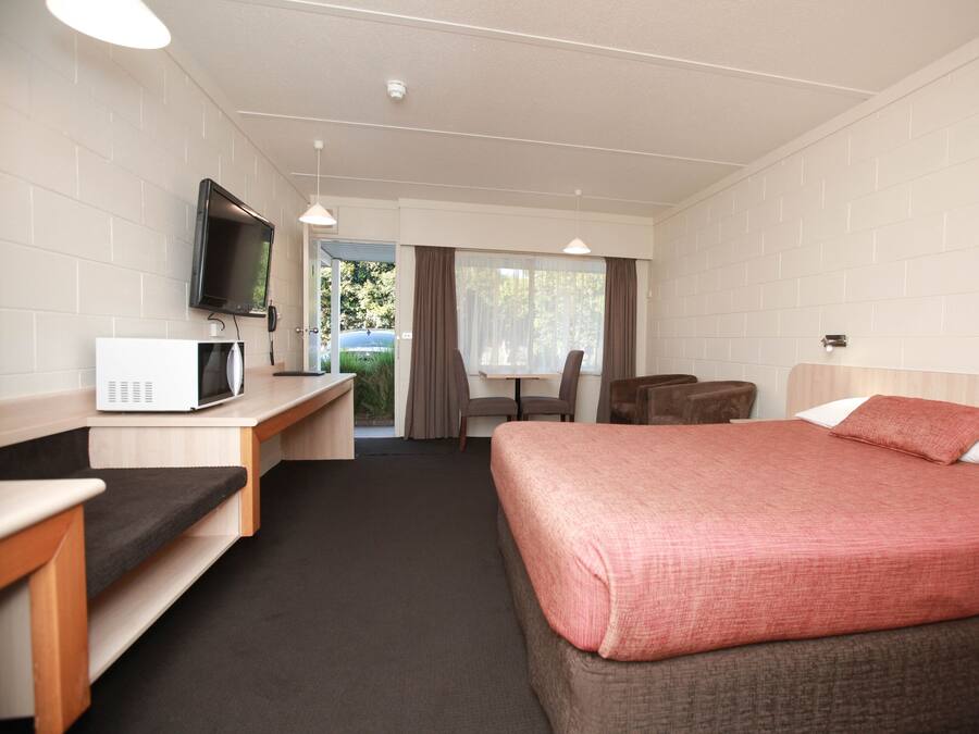 Ein Hotelzimmer mit Bett, Schreibtisch mit Mikrowelle, Fernseher und Blick ins Freie.