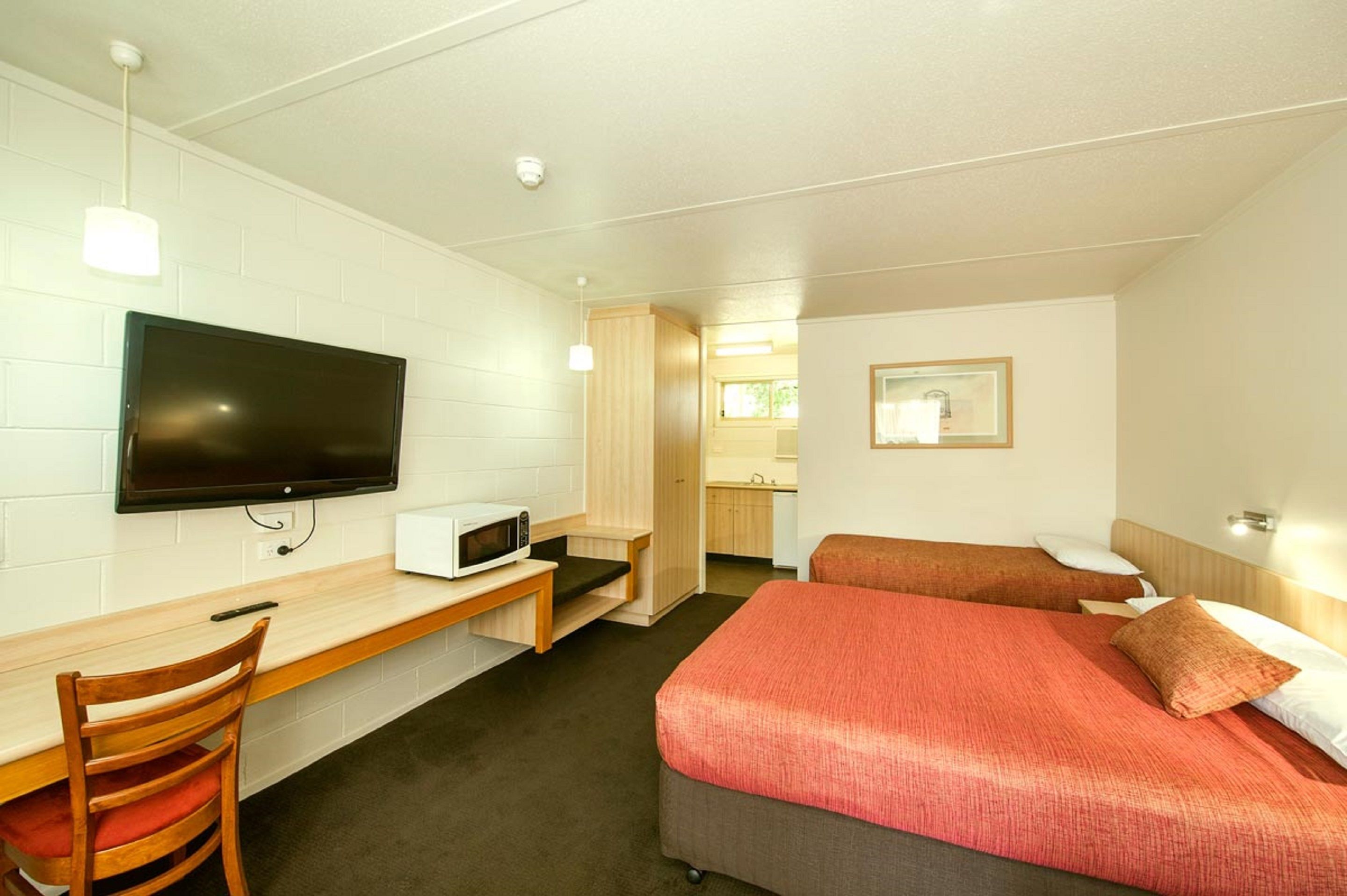A hotel room with a bed, a desk with a chair, a television, and a microwave.