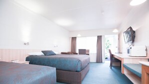 Quarto de hotel com duas camas, uma escrivaninha, televisão e janela com cortinas.