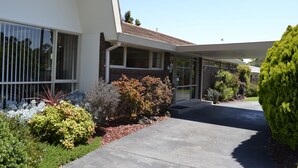 Uma casa moderna de dois andares com varanda coberta, janelas amplas e um jardim bem cuidado.