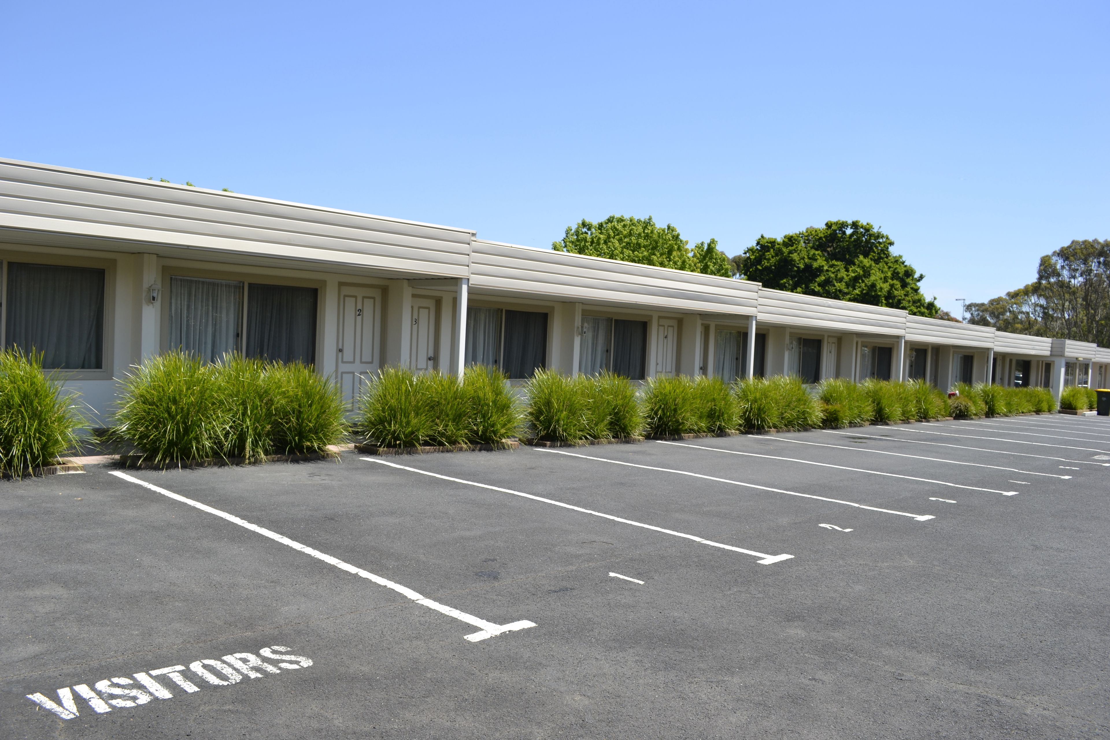 A row of motel rooms with a parking lot marked "VISITORS".