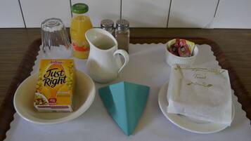 A tray with a box of Kellogg's Just Right cereal, a glass pitcher, a bottle of orange juice, salt and pepper shakers, a paper napkin, and a small bowl of strawberries.