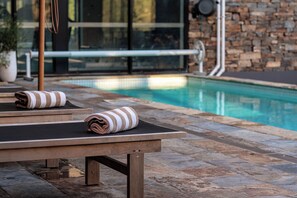 Ein Poolbereich mit Liegestühlen und Handtüchern, einer Steinmauer und einem klaren Pool.