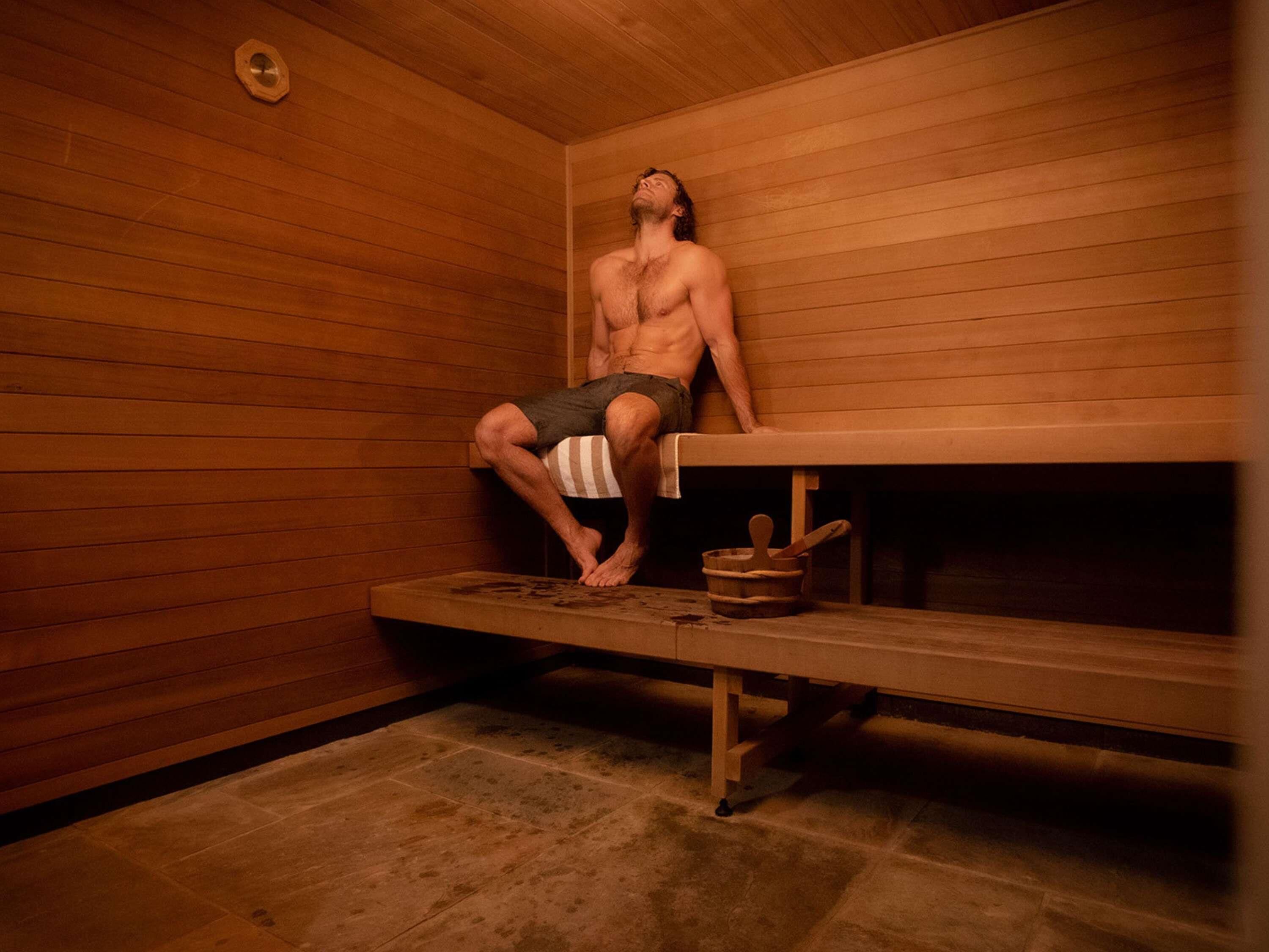 A sauna room with wooden walls, a bench, and a bucket.