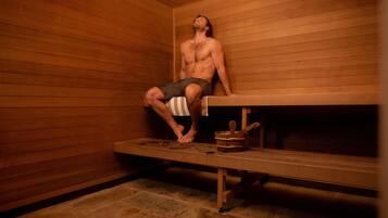 A sauna room with wooden walls, a bench, and a bucket.