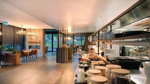 A modern kitchen with a long counter, various food items, and a dining area with wooden furniture. - Peppers Marysville (Marysville)