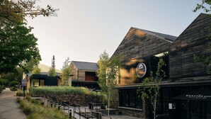A building with a sign that reads 'ANDIMO,' a paved walkway, and outdoor seating areas. - Peppers Marysville (Marysville)