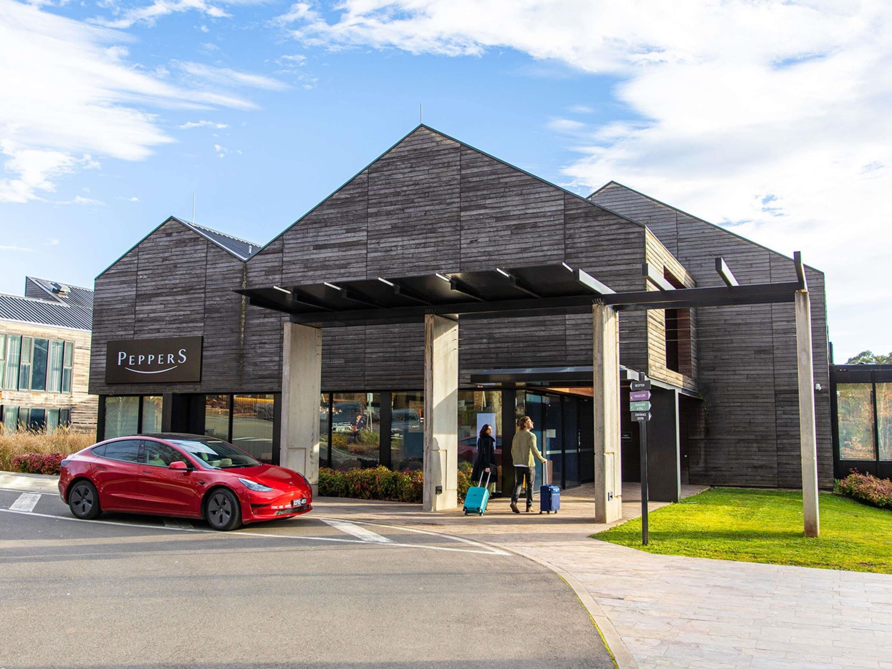 A modern building with a sign reading 'Peppers' and a red car parked in front.