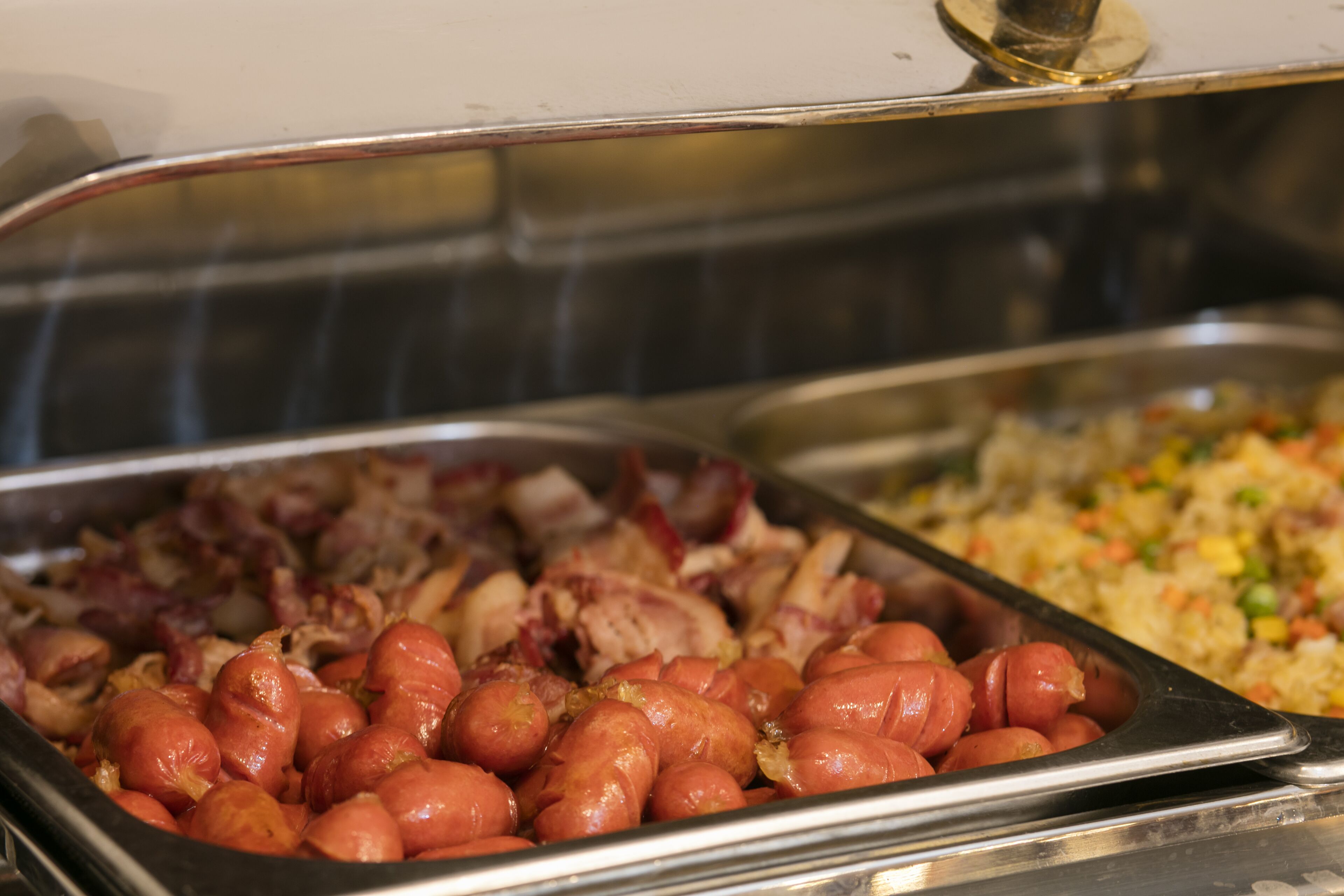 Ein Buffet mit verschiedenen Speisen, darunter Wurst und gebratenem Reis.