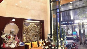 Un hall con mostrador de recepción, un muro decorativo y vistas al exterior.