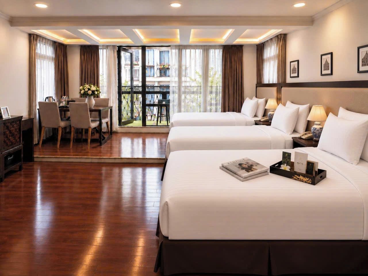 A hotel room with two beds, a dining table, and a balcony with curtains.