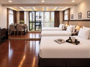 Ein Hotelzimmer mit zwei Betten, einem Esstisch und einem Balkon mit Vorhängen.