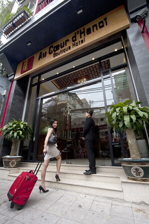 The entrance to Au Coeur d'Henot, a boutique hotel with a modern glass facade and a visible staircase leading to the entrance.