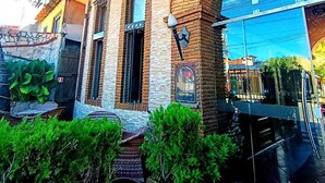 A building with a brick facade, arched windows, and a covered outdoor area with greenery. - Pousada Presidente Hotel (Aracati)