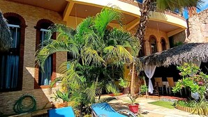 A multi-story building with a pool area, palm trees, and outdoor seating. - Pousada Presidente Hotel (Aracati)