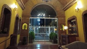 A lobby with a high, wooden ceiling and a chandelier. There are arched doorways and a glass door leading outside. - Pousada Presidente Hotel (Aracati)