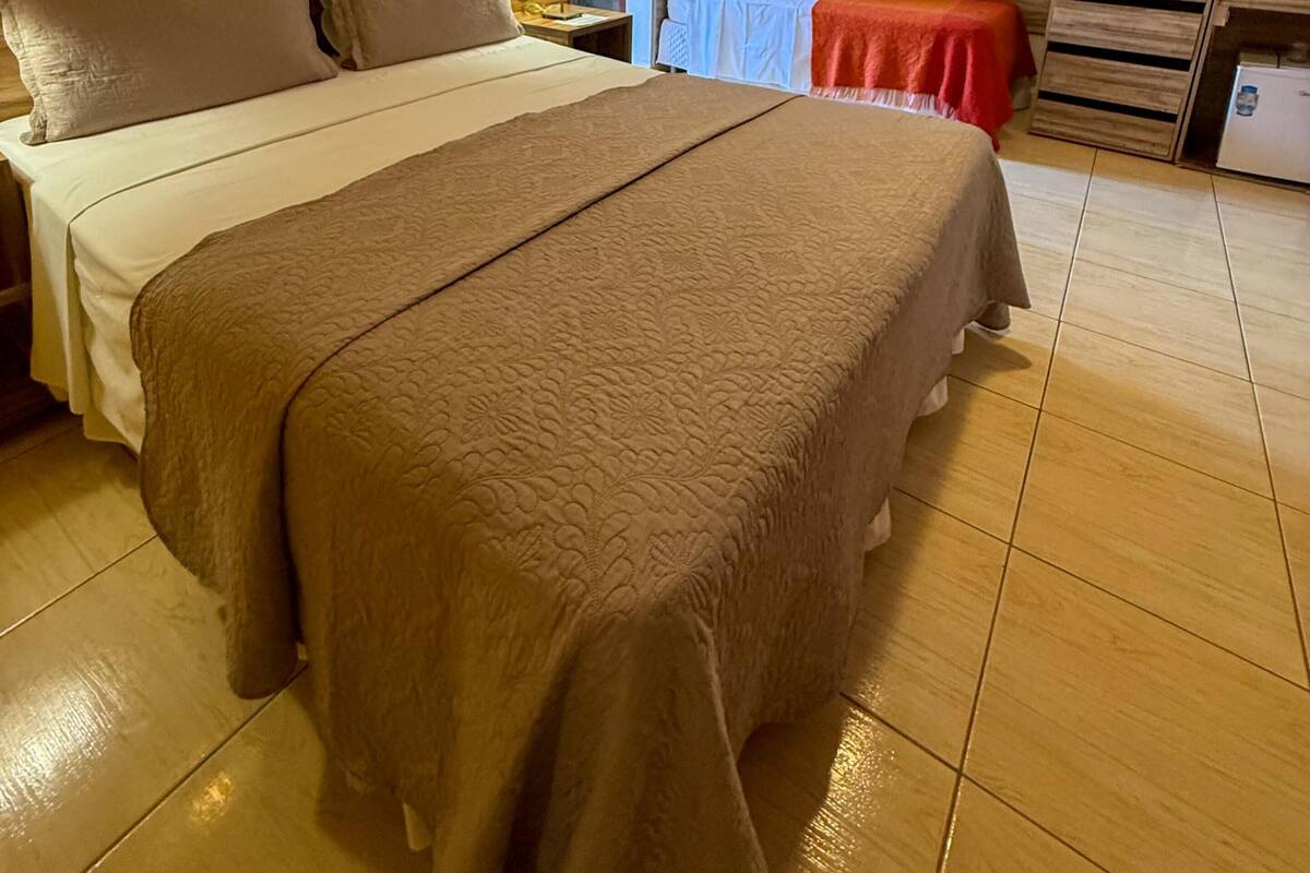 A hotel room with a large bed, a bedside table, a nightstand, a ceiling fan, and a window.