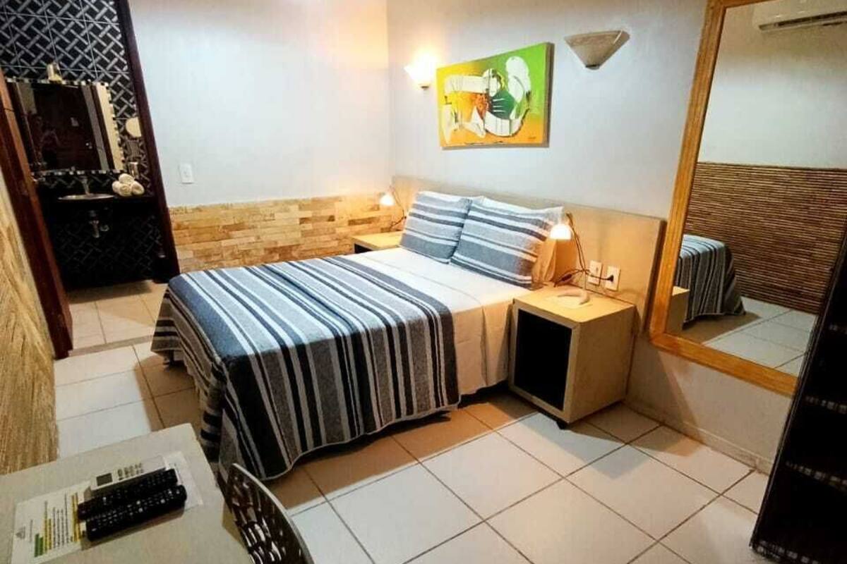 A bedroom with a bed, bedside tables, a desk, a mirror, and a wall-mounted artwork.
