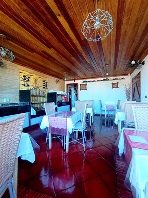 A restaurant with wooden ceiling, tiled floor, and tables with white tablecloths. - Pousada Presidente Hotel (Aracati)