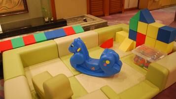 Children can play on the cushioned play mat with a geometric pattern, surrounded by foam blocks and a dinosaur toy.