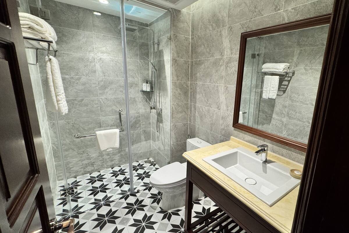 A modern bathroom with a glass-enclosed shower, a toilet, and a sink with a mirror above it.