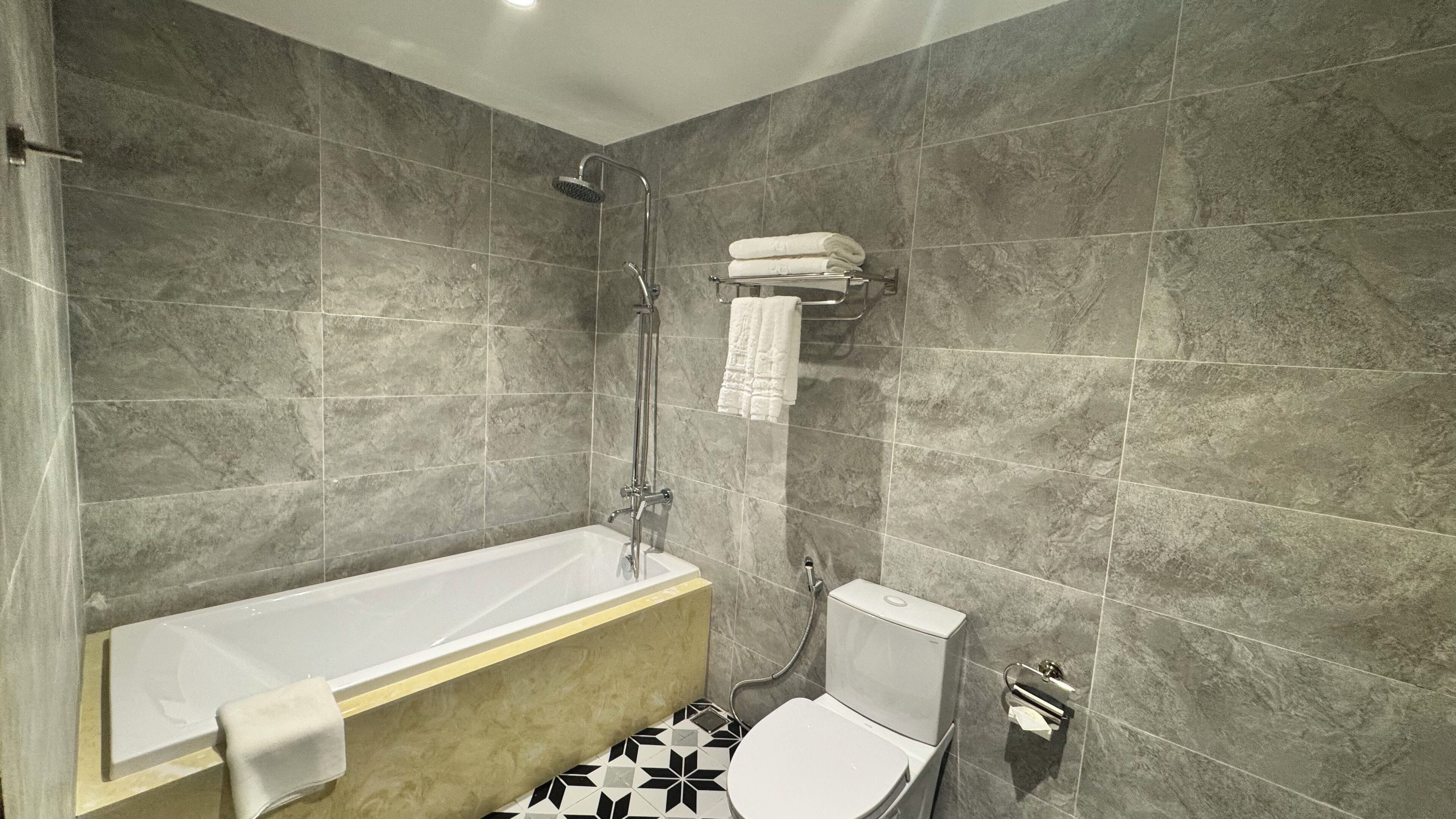 A modern bathroom with a bathtub, toilet, and shower.