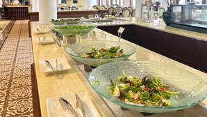 Ein Buffetbereich mit Glasvitrinen, gefüllt mit Salaten, einem gemusterten Boden und einer dekorativen Decke.