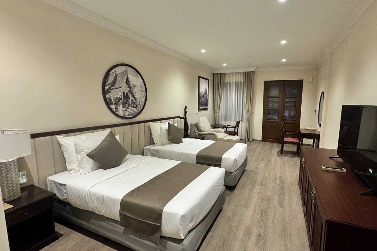 A hotel room with two beds, a TV, a desk, and a chair.