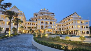 Ein großes, mehrstöckiges Hotel mit einem prachtvollen Eingangsbereich, mehreren Balkonen und einem gut beleuchteten Innenhof.