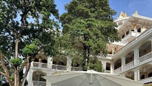 Ein Poolbereich mit Liegestühlen und Sonnenschirmen, umgeben von einem mehrstöckigen Gebäude mit Balkonen.