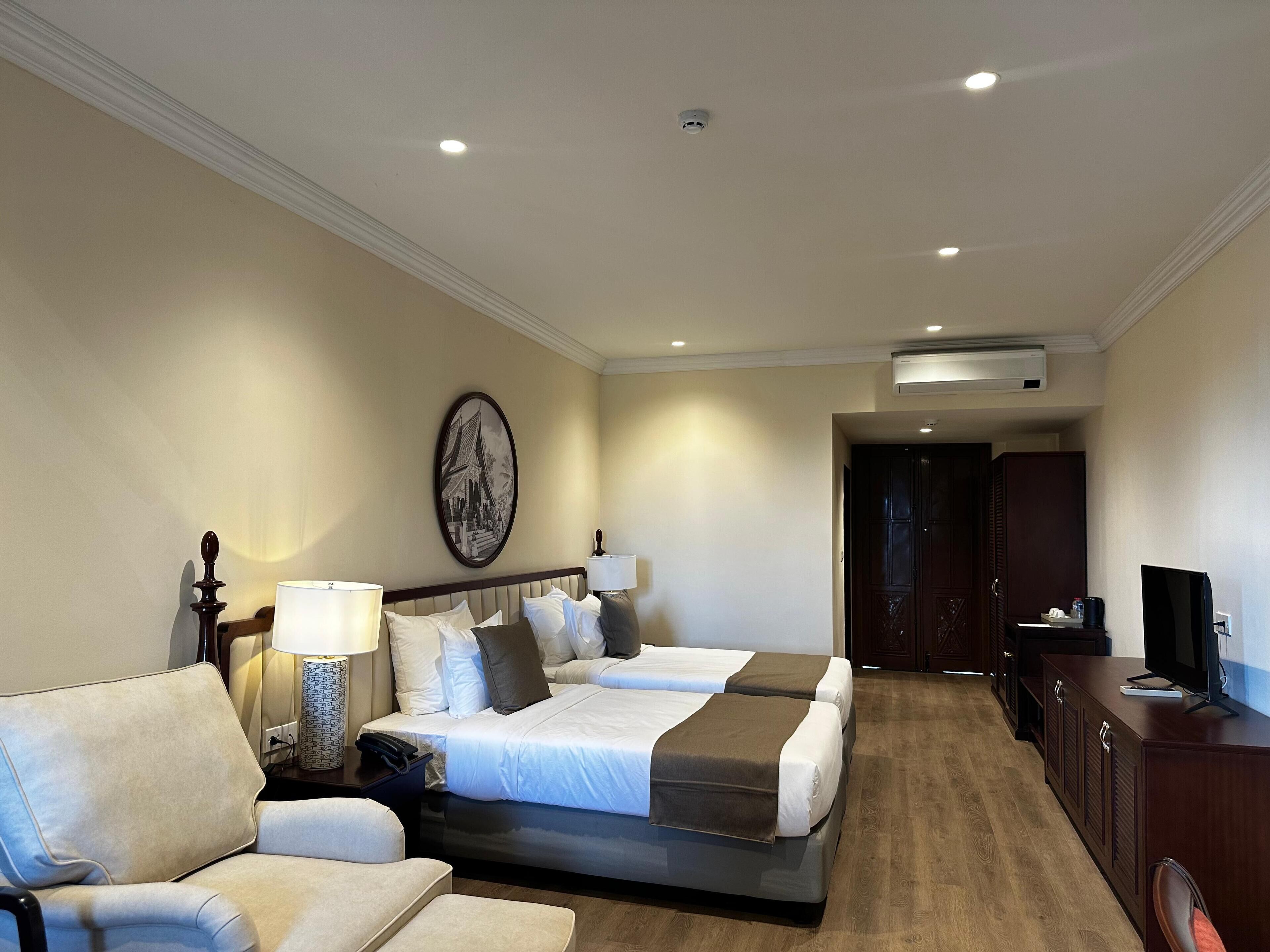 A hotel room with a bed, a sofa, a desk, and a TV.