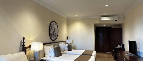 A hotel room with a bed, a sofa, a desk, and a TV.