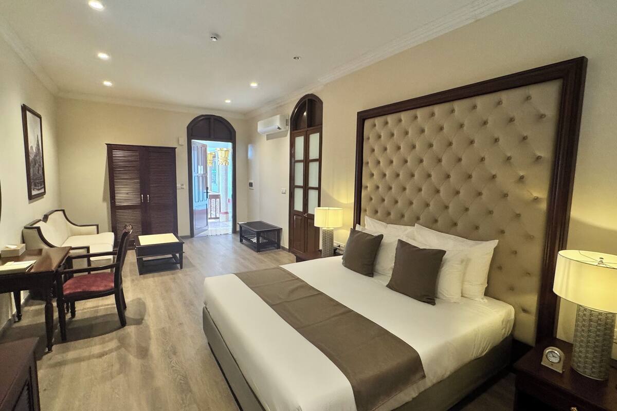 A hotel room with a large bed, a desk, a chair, and a small table.