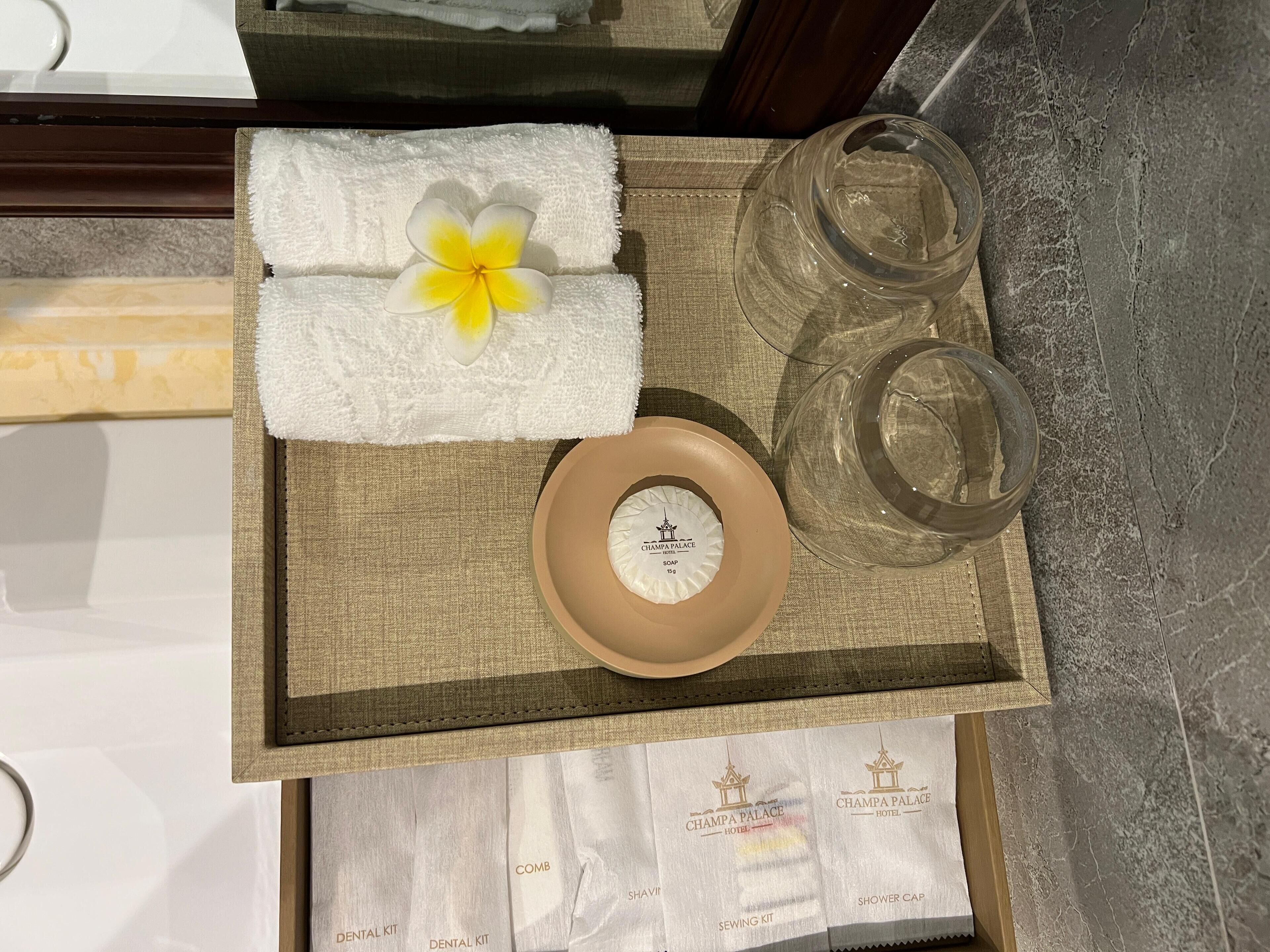 A tray with a towel, a comb, a sewing kit, and two glasses.