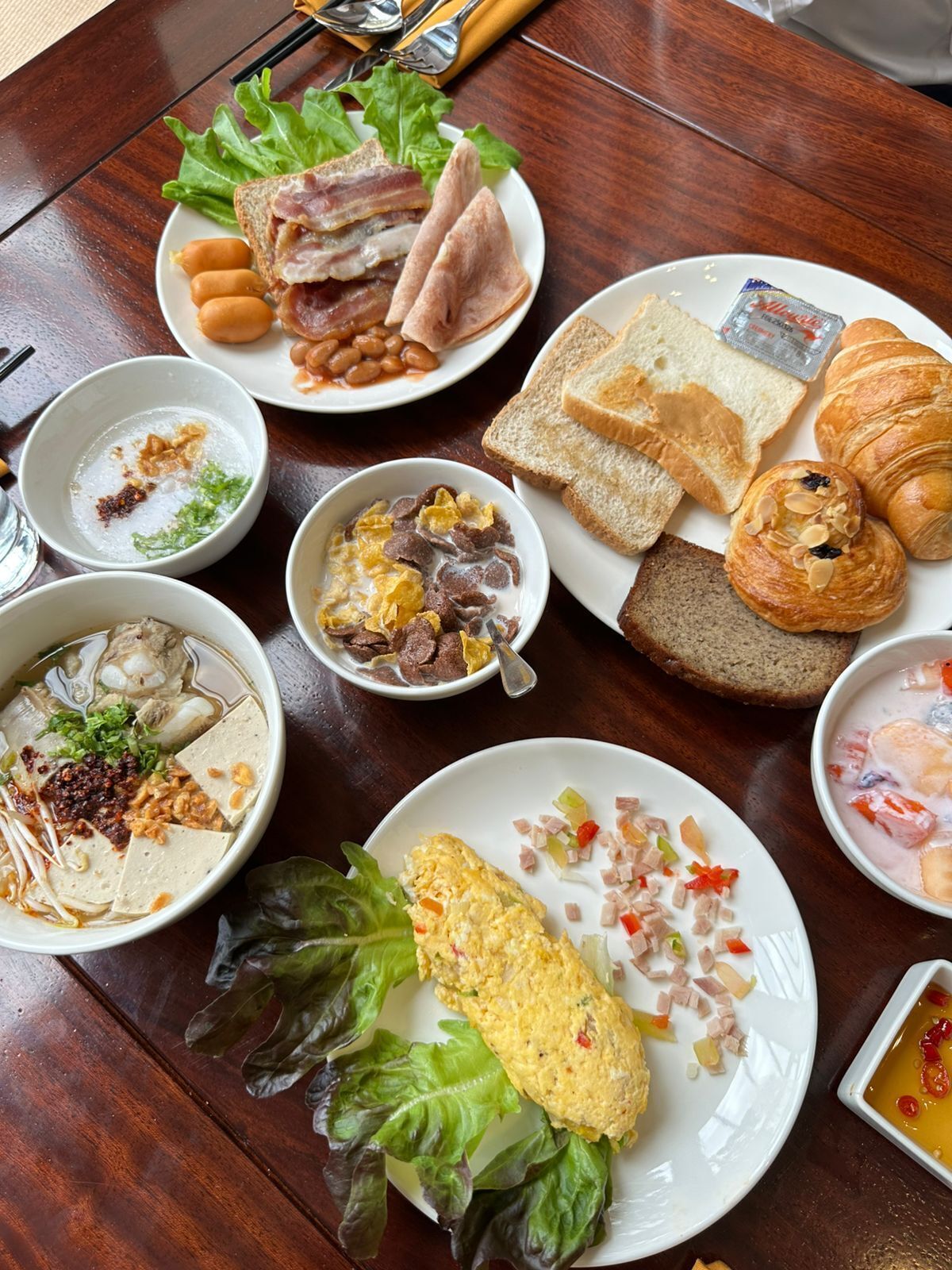 Une table avec divers aliments pour le petit-déjeuner, notamment des toasts, des croissants et un bol de soupe.