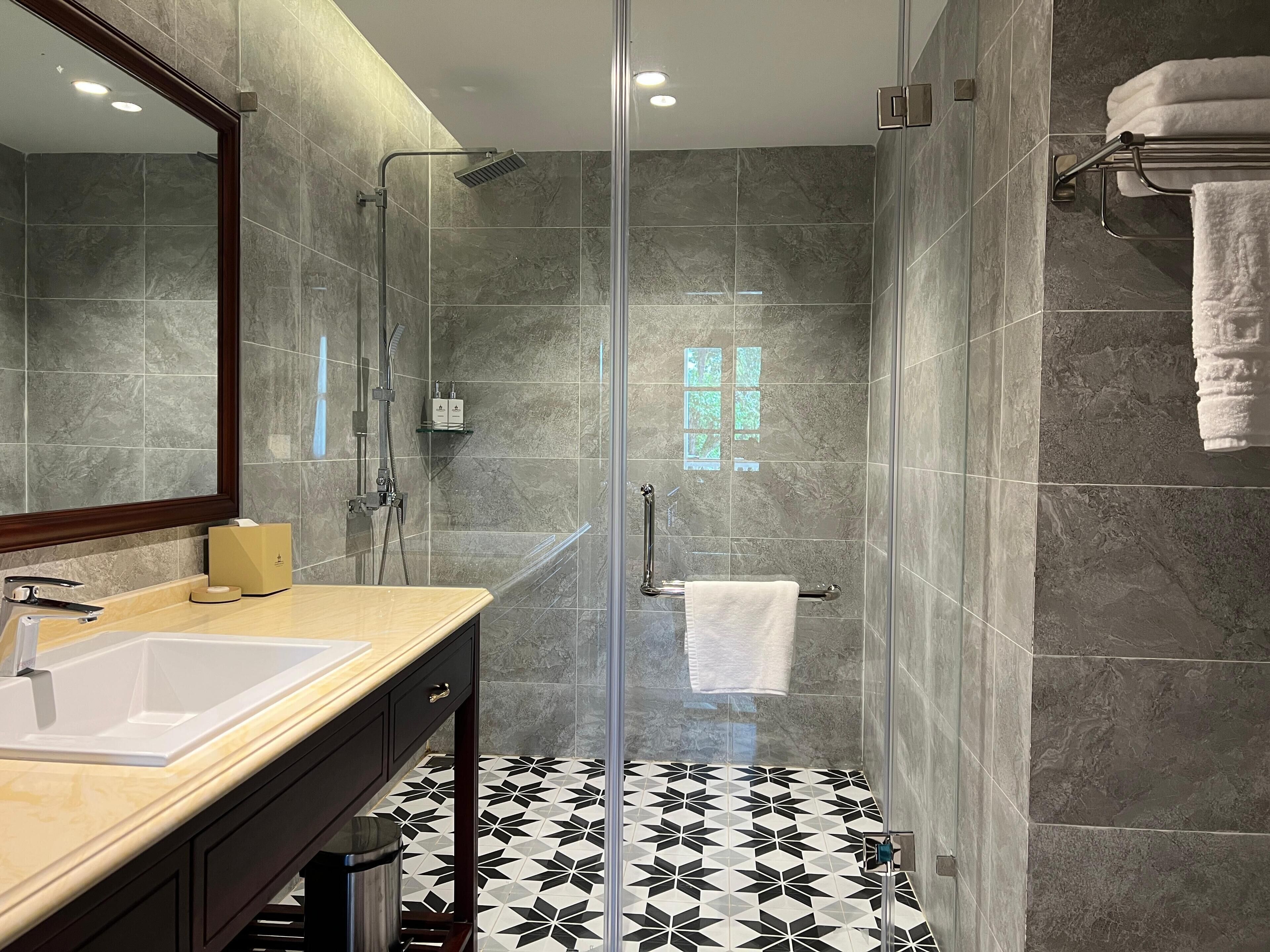 A modern bathroom with a glass-enclosed shower, a vanity with a sink, and a towel rack.