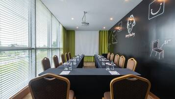 Ein Konferenzraum mit langem Tisch, Stühlen, einem Projektor und einer Wand mit Kreideanschriften.