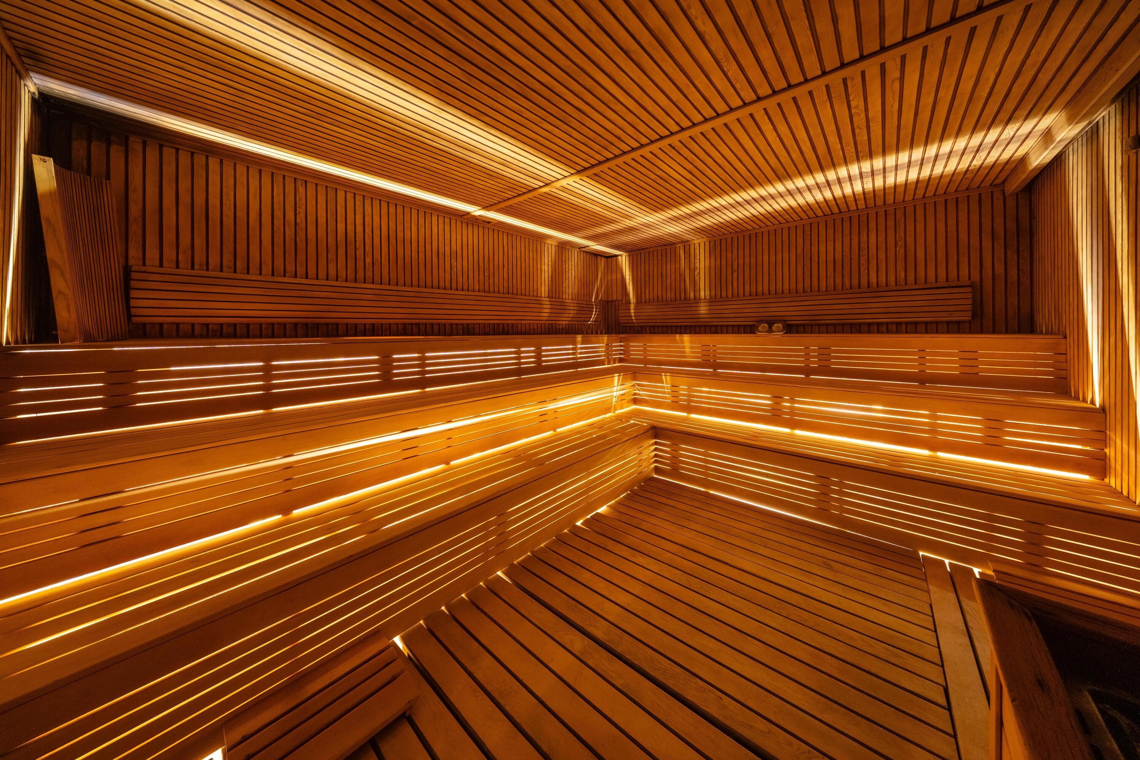 A sauna with wooden slats and benches, and a sloped ceiling.