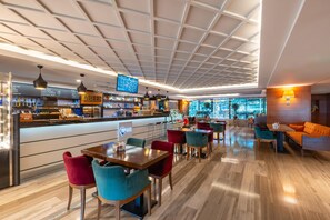 A modern bar area with a digital menu, seating with colorful chairs, and a view through large windows. - Park Inn by Radisson Istanbul Asia Kavacik (Beykoz)