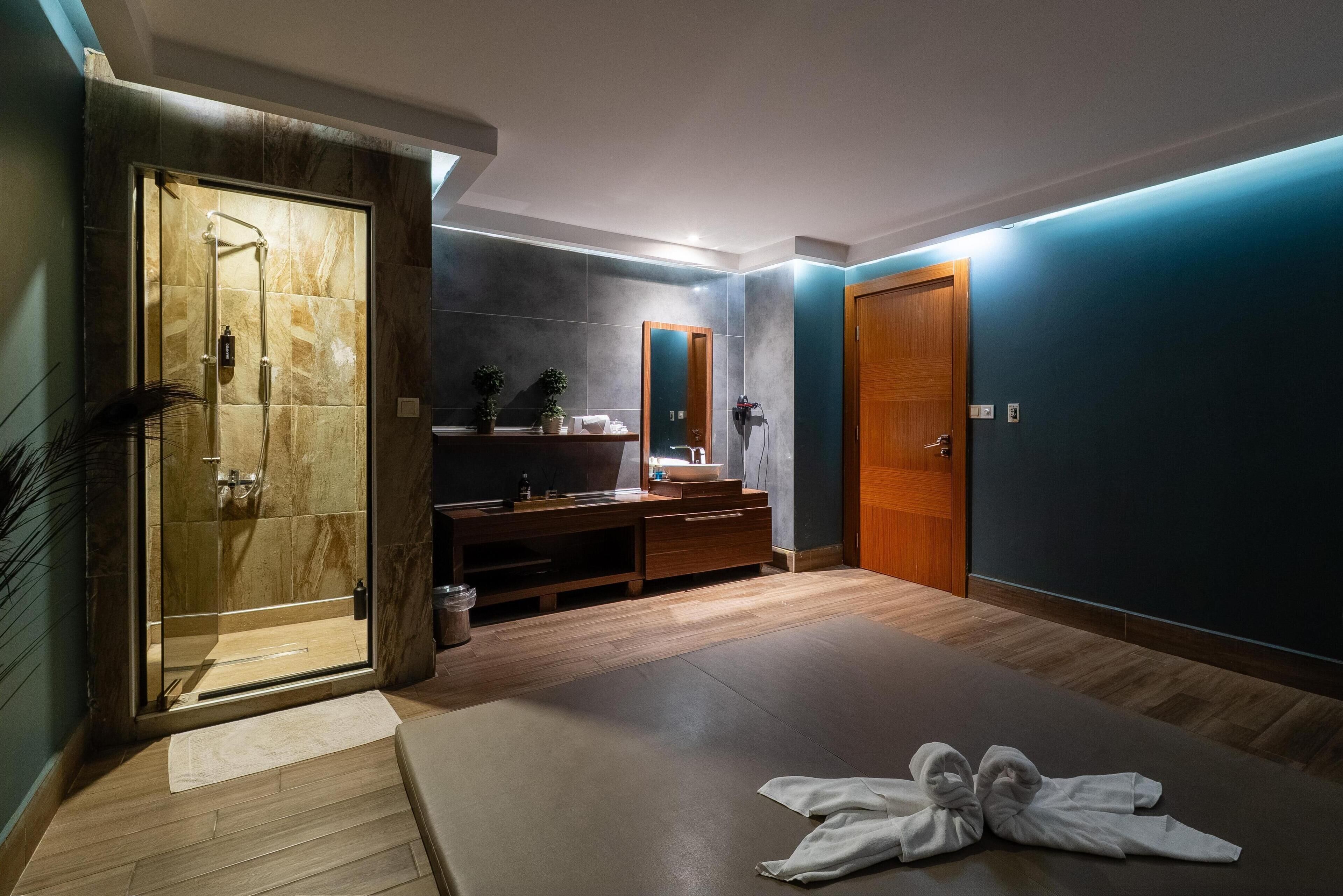 A modern bathroom with a glass-enclosed shower, a wooden vanity with a sink, and a large mirror.