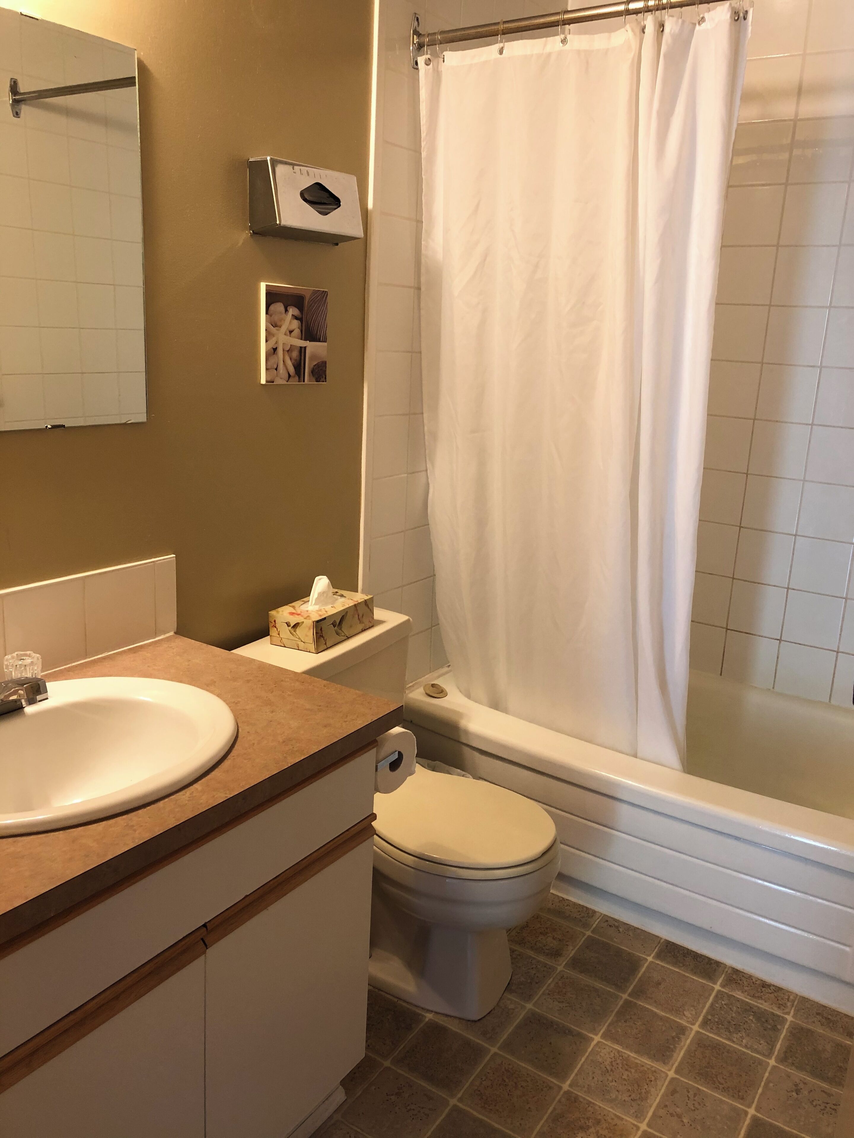 Et badeværelse med håndvask, toilet og badekar.