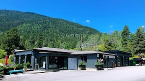 A small, two-story building with a flat roof, large windows, and a parking area in front. - Kokanee Glacier Resort (Nelson)