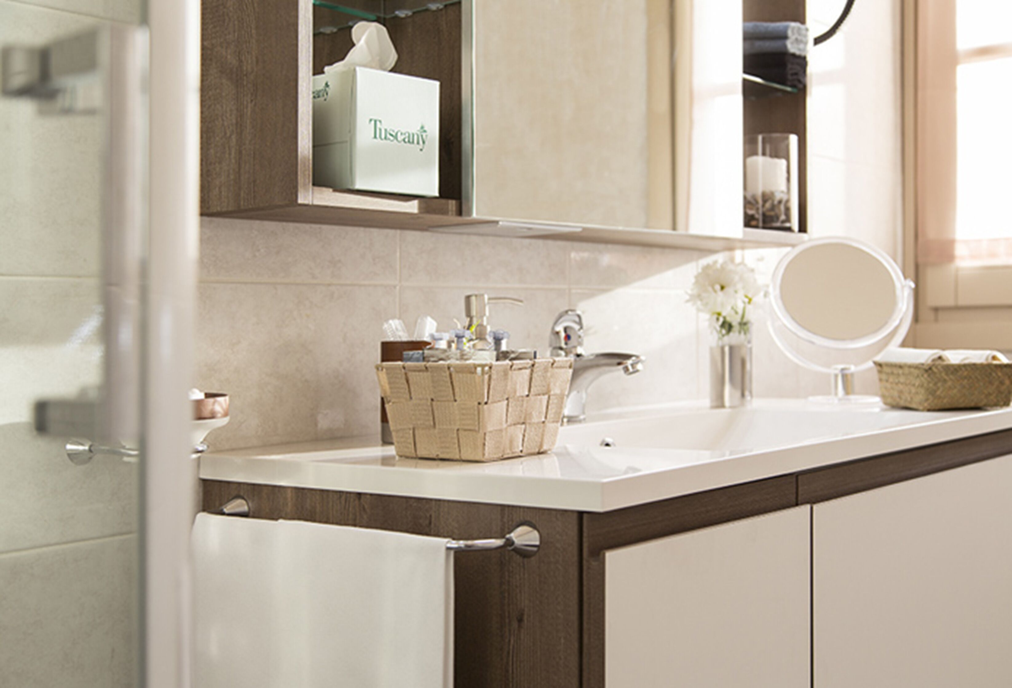 Une salle de bain avec un lavabo blanc, un miroir, un panier contenant des articles de toilette et un porte-serviettes.