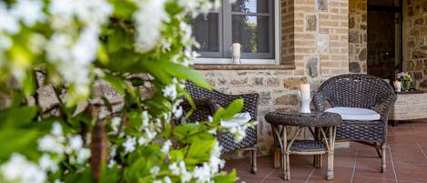 A patio area with wicker furniture, a stone wall, and a window.