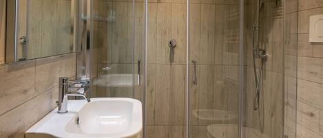 Un baño moderno con ducha de vidrio, lavamanos doble y retrete.