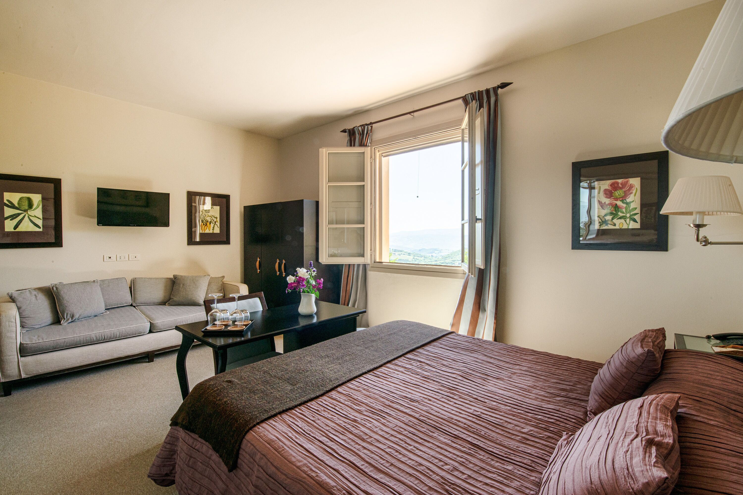 A hotel room with a bed, a sofa, a desk, and a TV.